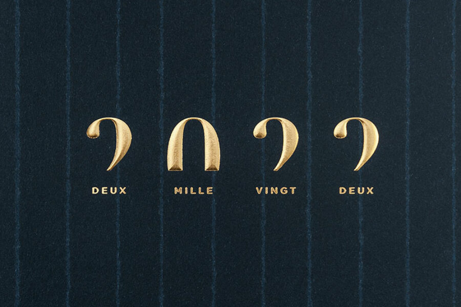 Cette photo représente un zoom de la carte de vœux modèle Typote, de la collection Intaglio 2022, sur une carte Bleu Savile Row, avec le détail de la gravure Or gaufrante.