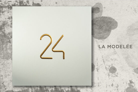 Mise en scène du modèle de carte de voeux de luxe 2024, La Modelée, dans sa version Or sur Bianco, sur un fond original.