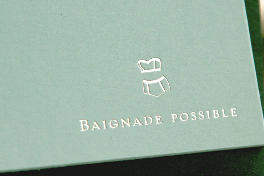 Faire-part de mariage avec un pictogramme illustrant un bikini et Baignade possible gravé or blanc sur papier pistachio par l'imprimerie Intaglio